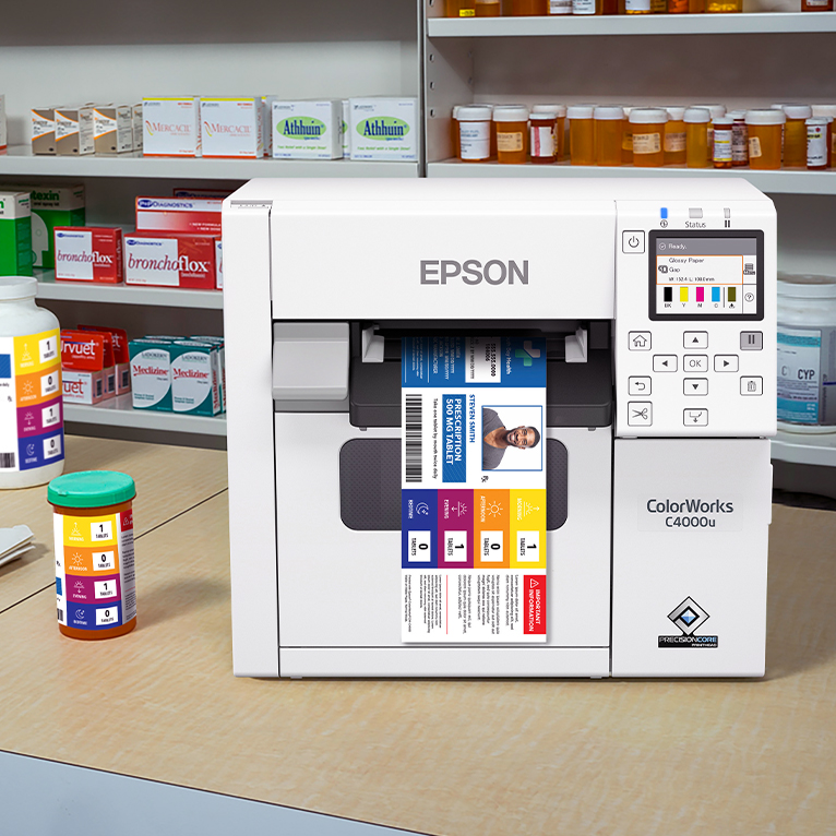 An Epson ColorWorks C4000 printer on a pharmacy countertop, printing medication labels.
