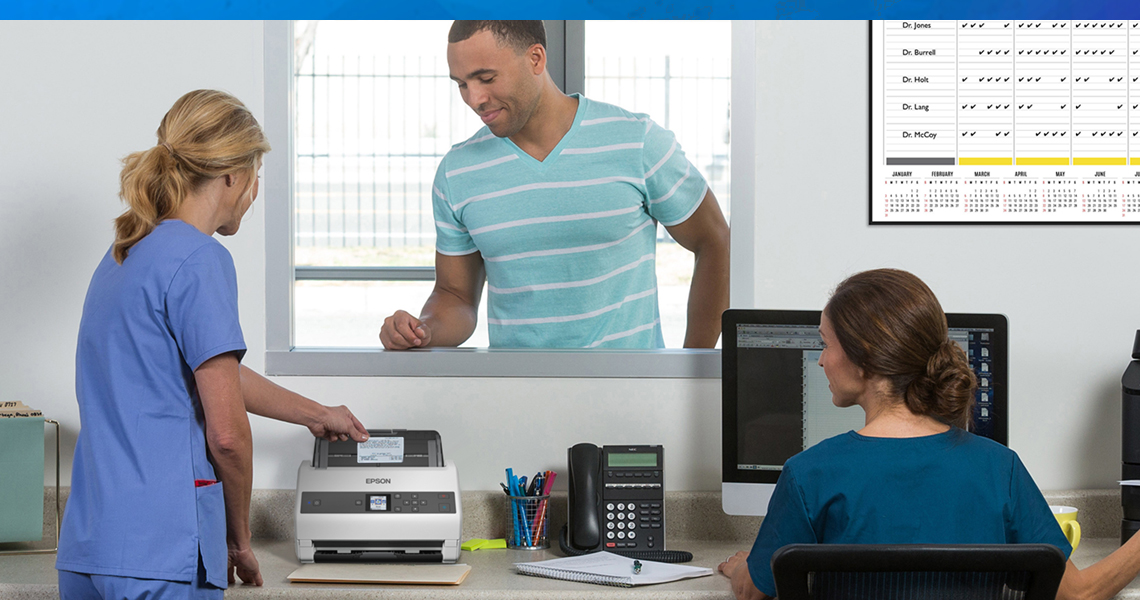 Three people in an office using a scanner