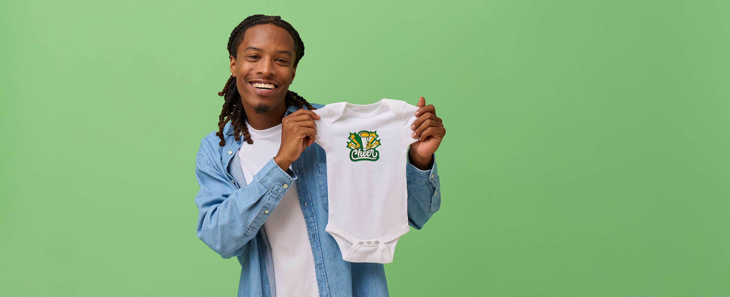 Smiling man holding baby onesie printed with cheer team design.