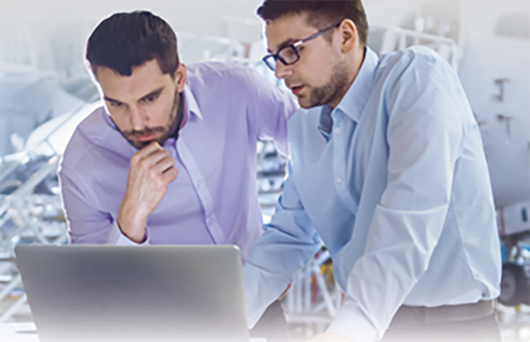 two men in dress shirts attentively looking at a gray laptop