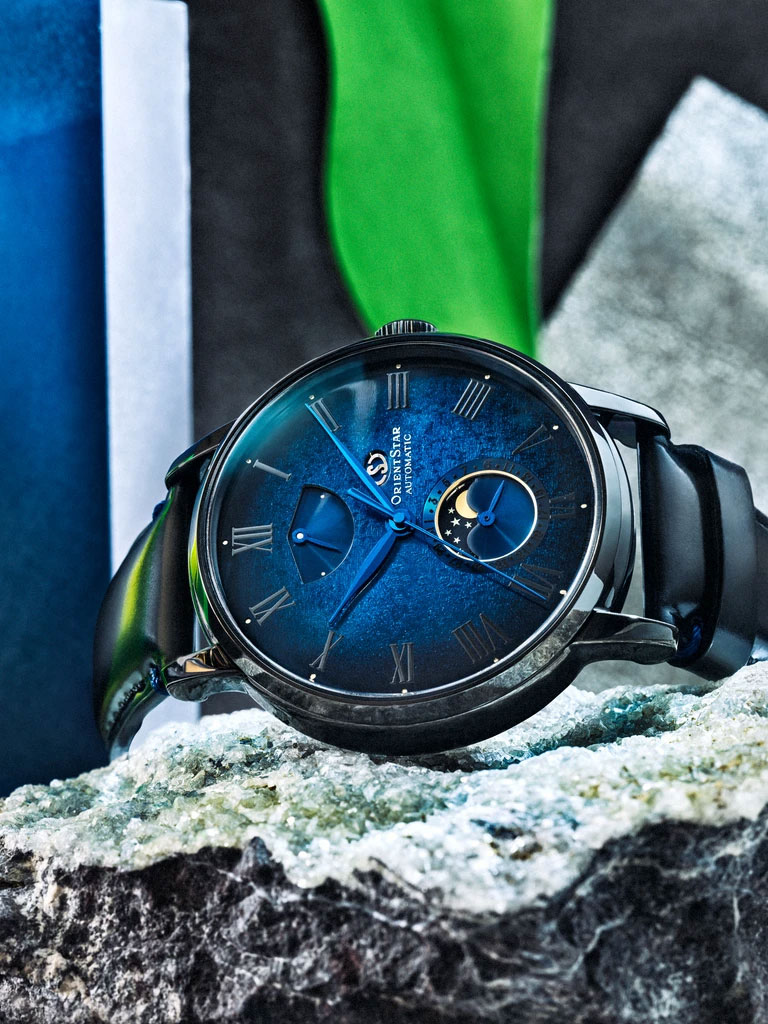 Orient Star's new M45 F7 Mechanical Moon Phase watch laying sideways on a crystalized rock