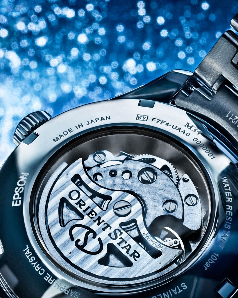 The display caseback and movement of an Orient Star M34 F7 Semi Skeleton on a shimmering backdrop