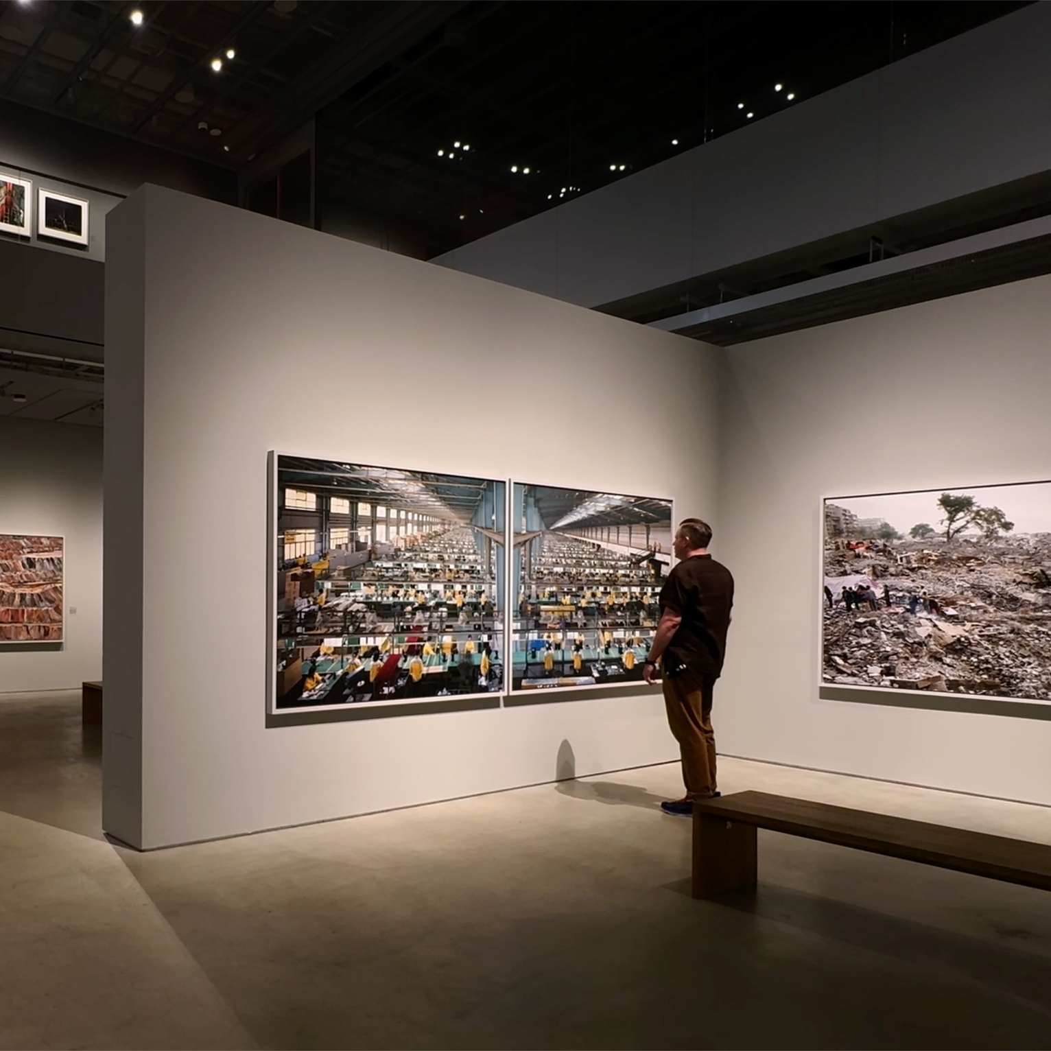A man stands in a gallery viewing Edward Burtynsky prints.