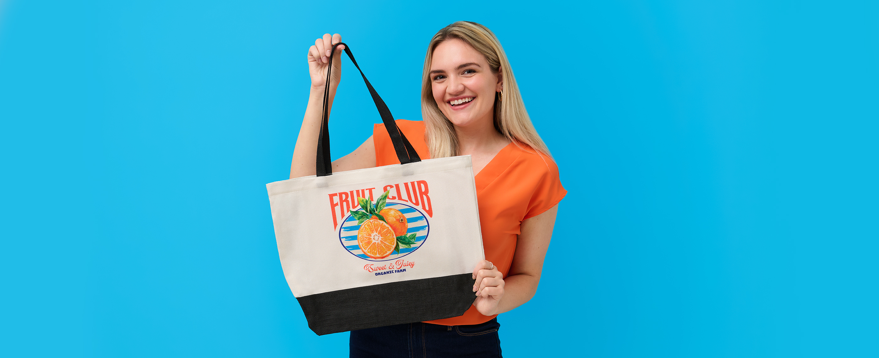 Tote bag printed with orange fruit design held by a smiling woman.
