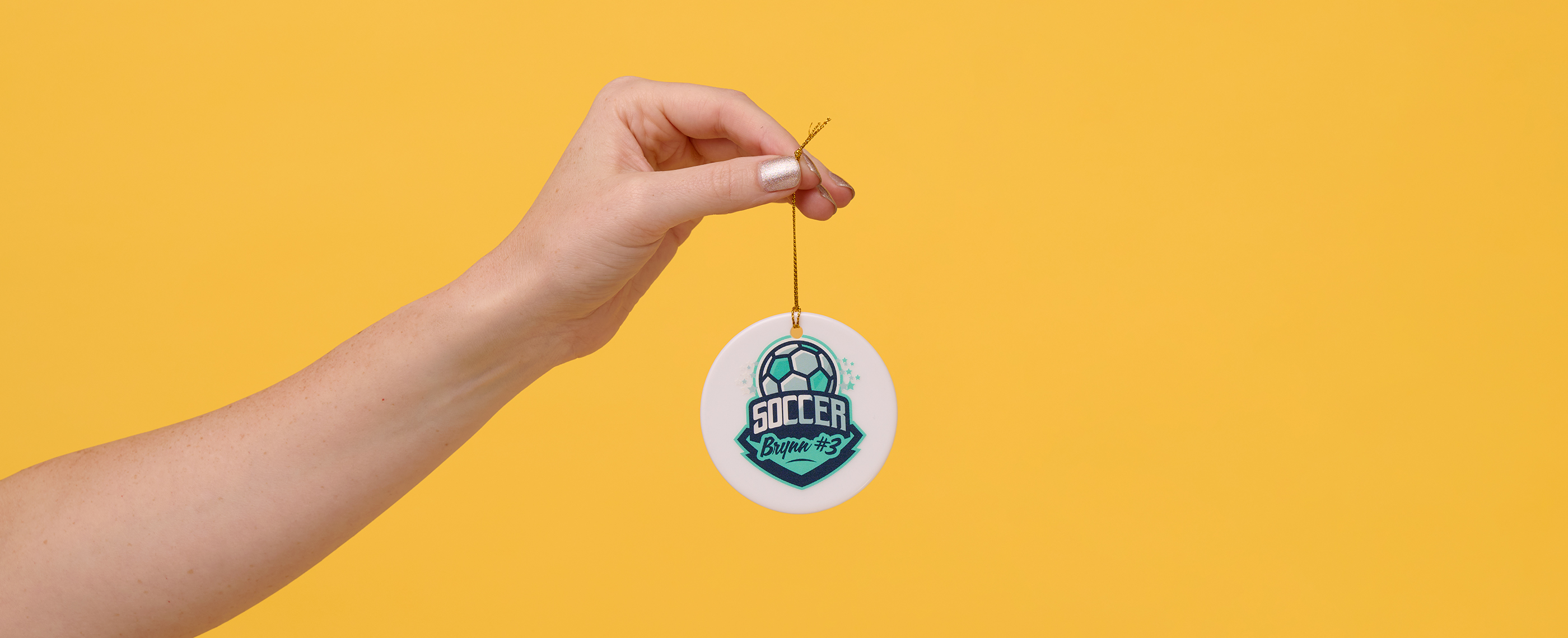 A hand holding an ornament printed with a soccer team logo.