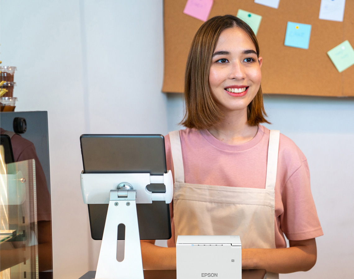 Cashier at cafe checkout with Epson receipt printer
