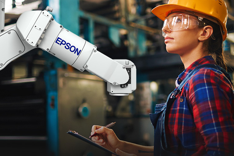 A female engineer in a hard hat and safety glasses observes an Epson robotic arm in a factory setting, holding a clipboard.