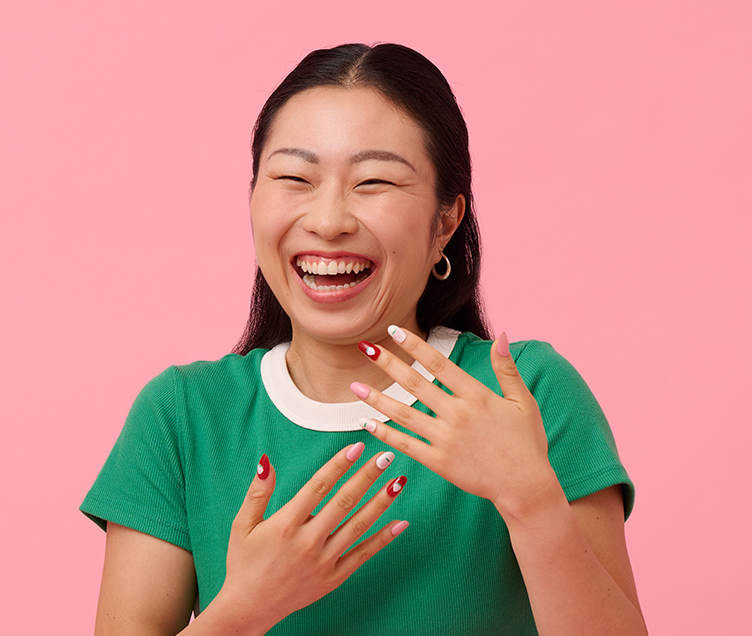 A smiling woman wearing press-on nails printed with strawberry designs.
