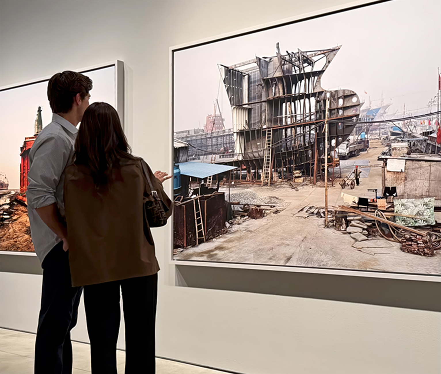 Two people stand in a gallery viewing Edward Burtynsky prints.