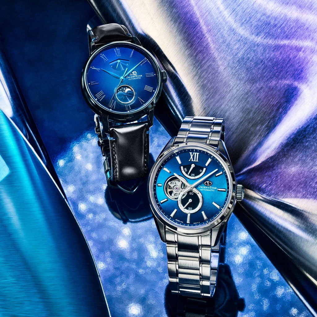 Two Orient Start M Collection watches on a blue metallic backdrop.