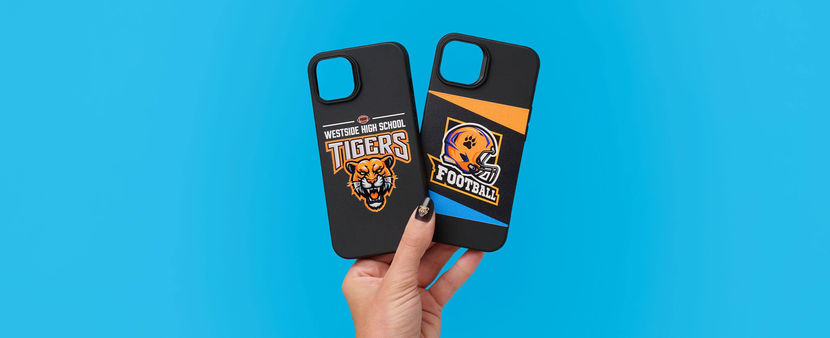 A hand with press-on nails printed with tiger mascot designs, holding phone cases with matching graphics.