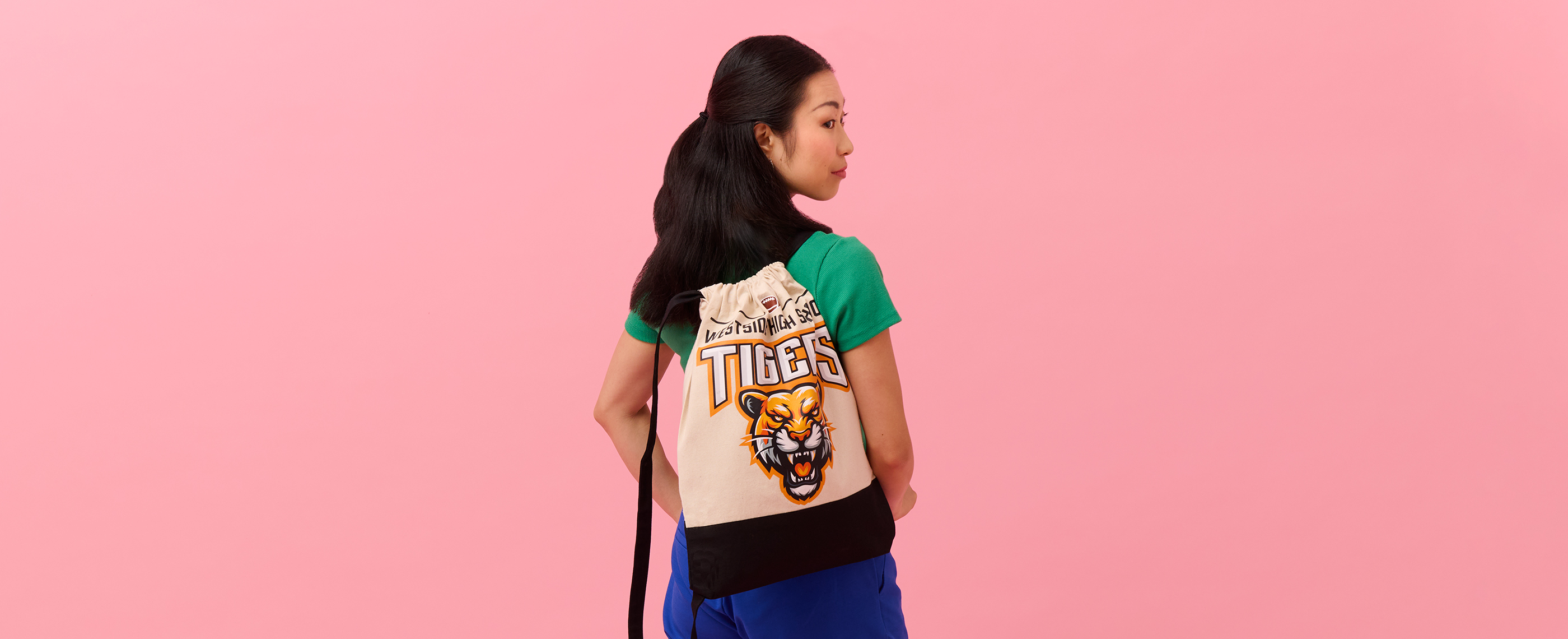 Woman wearing backpack tote printed with high school mascot design.