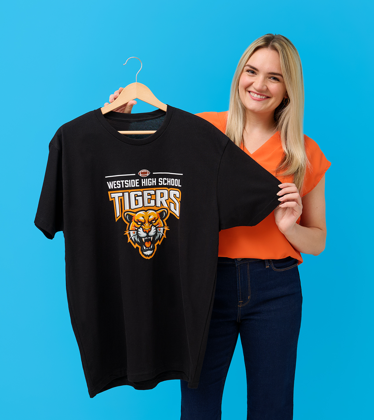 A woman holding t-shirt printed with a high school mascot design.