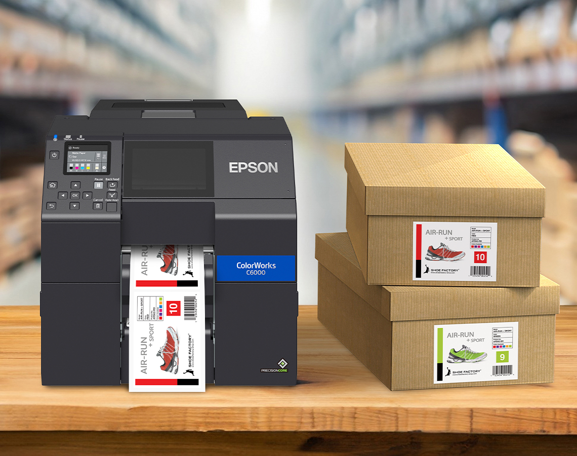 An Epson ColorWorks C6000 printer printing shoebox label next to shoebox stack in a warehouse.