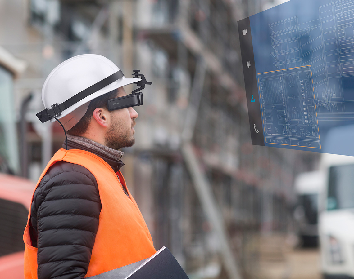 Construction worker wearing Epson smart glasses looking at a digital blueprint.