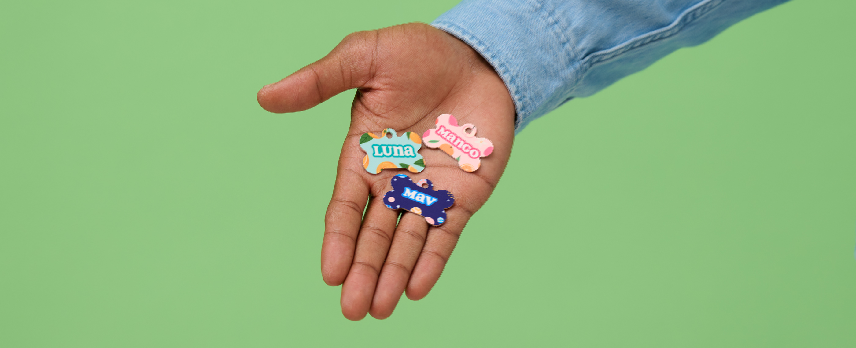 Bone-shaped pet tags with fruit and outer space patterns.