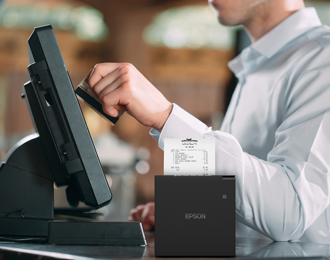 A man sliding a credit card at a kiosk with an M-Series printer
