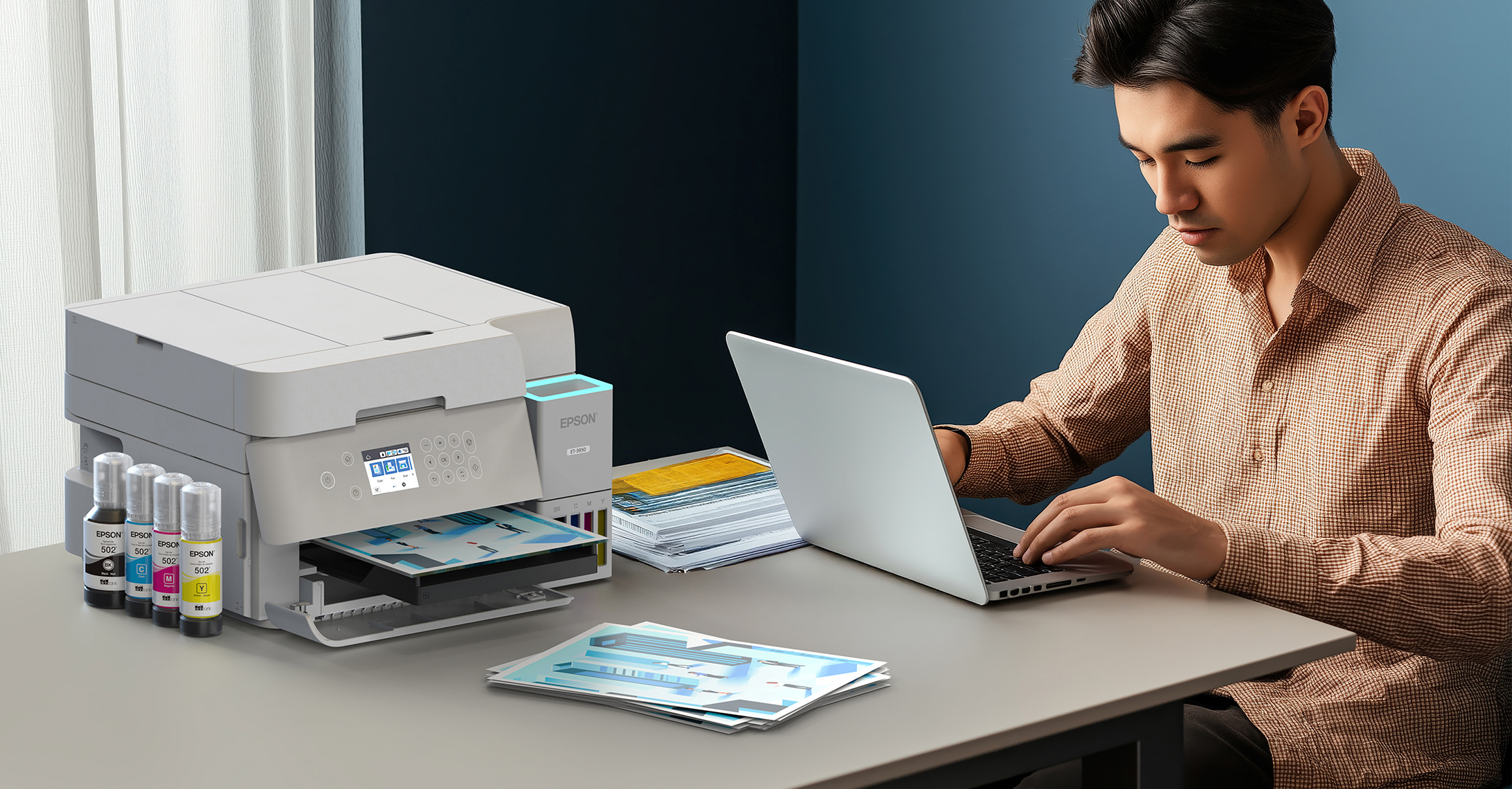 Man seated at a desk with a laptop and EcoTank printer.