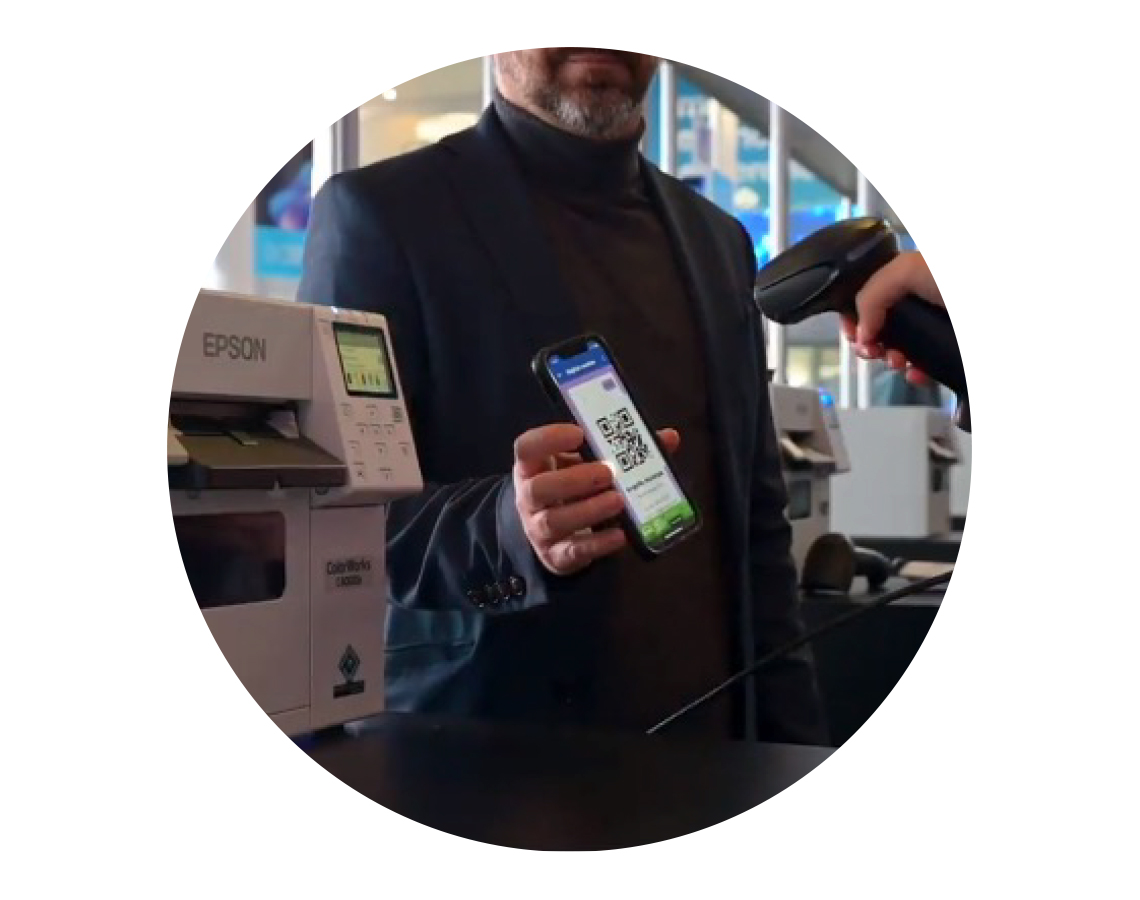 A man scanning a QR code on a phone next to Epson ColorWorks C4000 printers at Fira de Barcelona.
