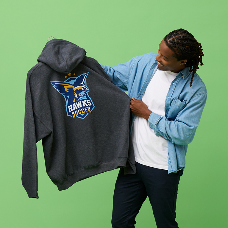 A man looking at a hoodie printed with a soccer mascot.