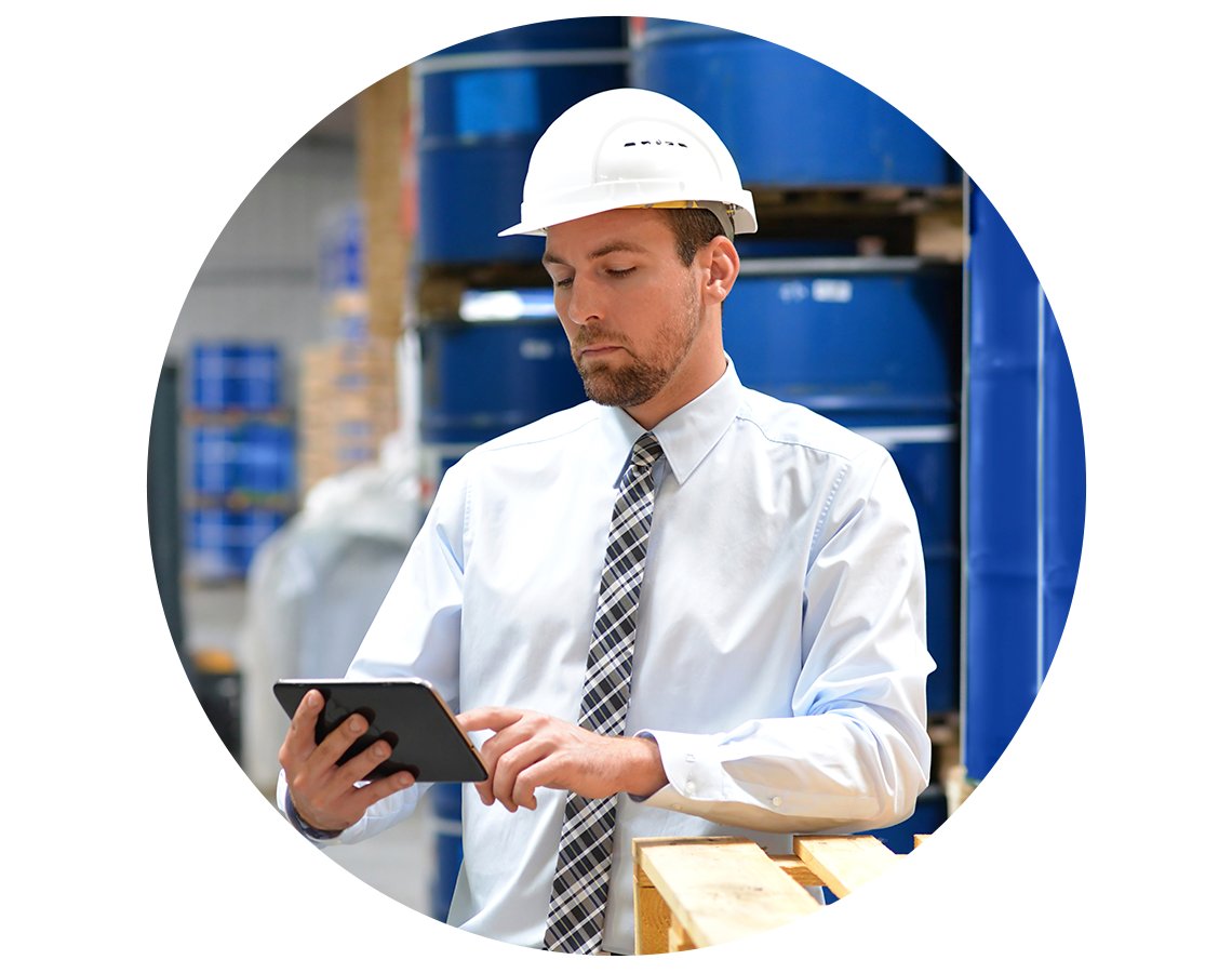 A chemical warehouse manager looking at a digital tablet in his hand.