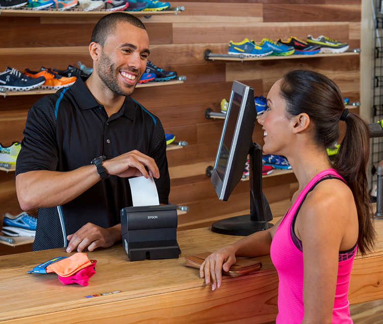 Shoe Store Retail clerk pulling a receipt from a printer for a customer