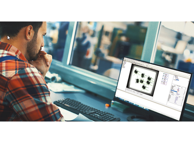 A man in a plaid shirt focused on his computer screen, which displays electronic circuit designs, in a modern office setting.