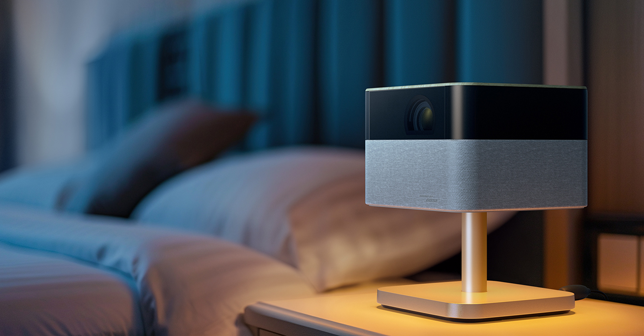 A Lifestudio Flex projector on a bedroom nightstand
