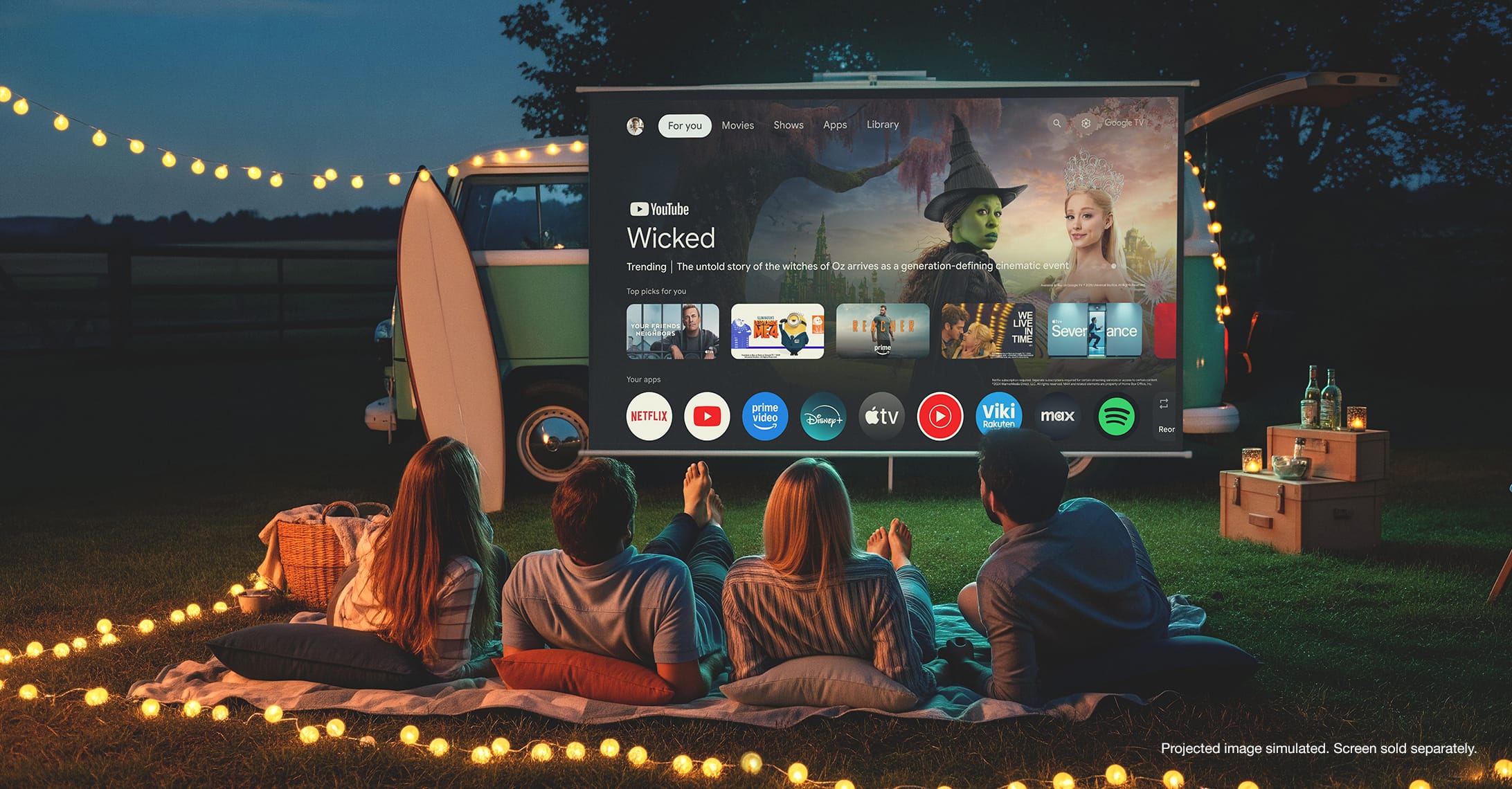 A group of adults watching a projector outdoors. There is a Google TV interface on the projection screen.  Projected image simulated. Screen sold separately.
