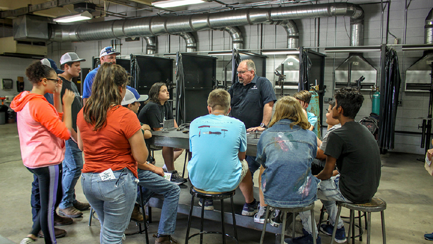Teacher giving a robotics lesson to students sitting around a table