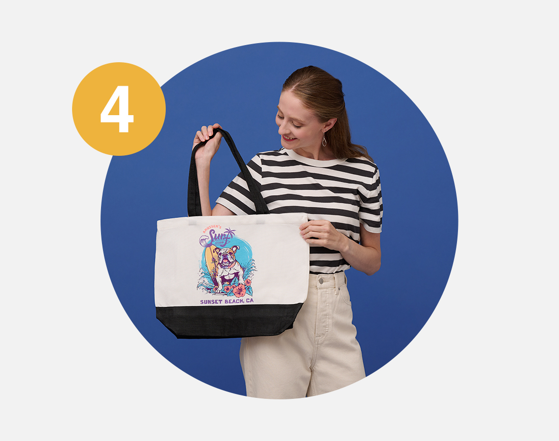 Smiling woman holding tote printed with surf dog mascot design.